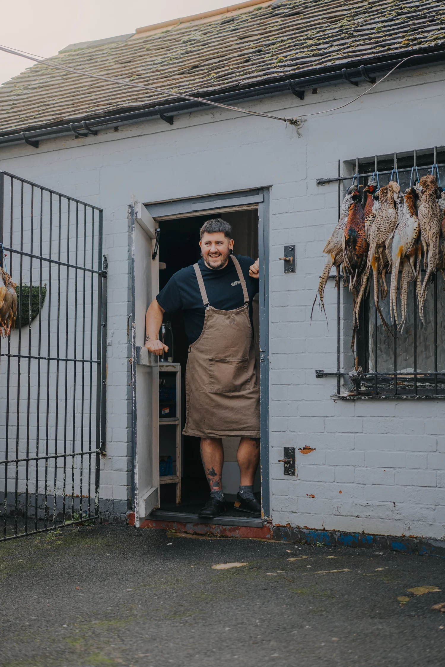 A chef smiling in the doorway of a restaurant.